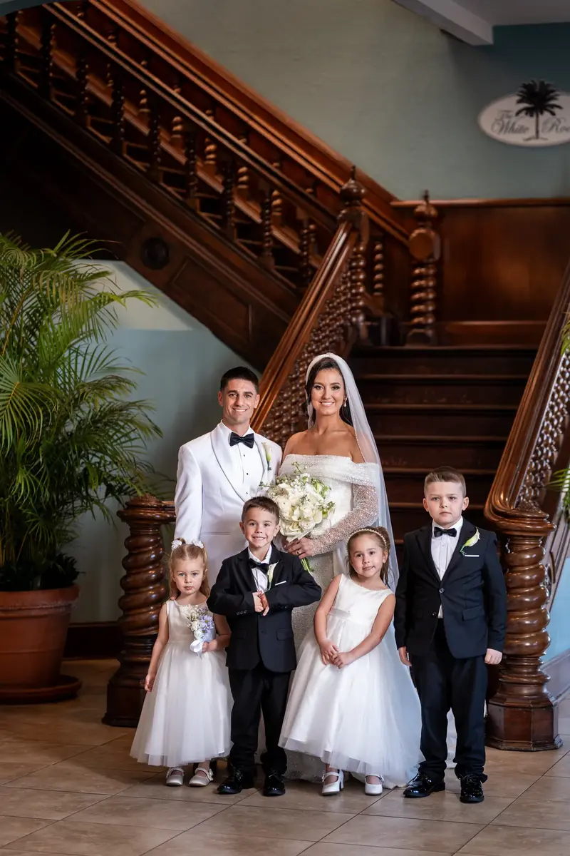 Couple with flower girls and ring bearers on grand wooden staircase