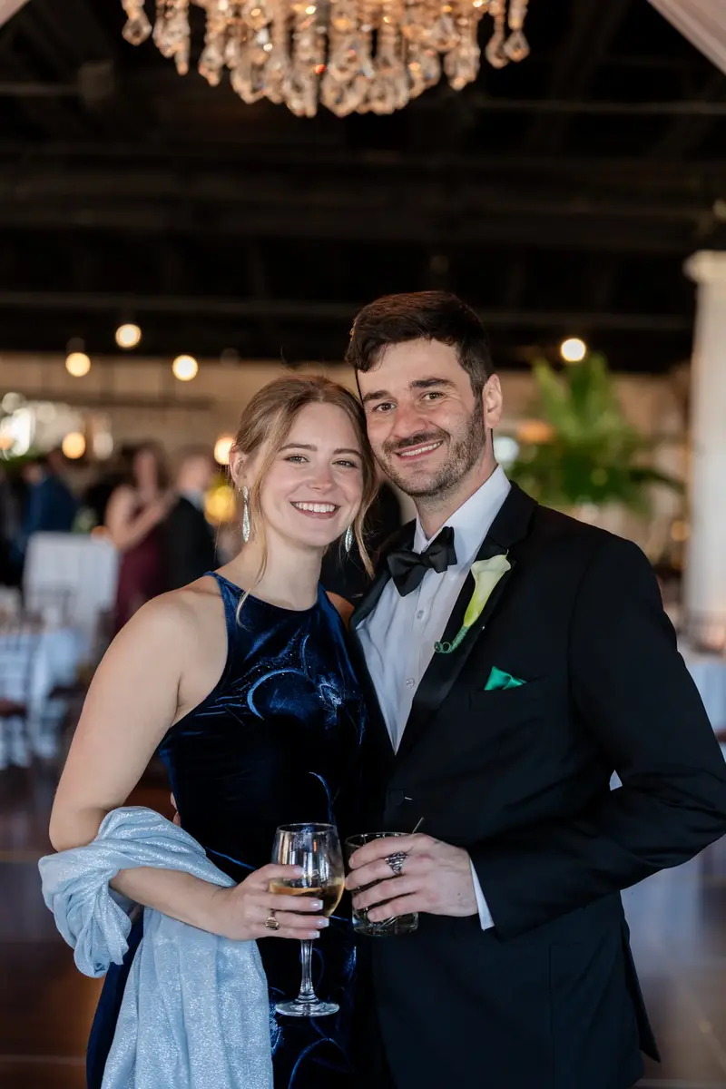 Wedding guests smiling with drinks under chandelier at reception