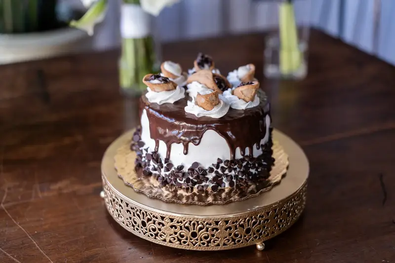 Chocolate drip wedding cake with meringue decorations on gold stand
