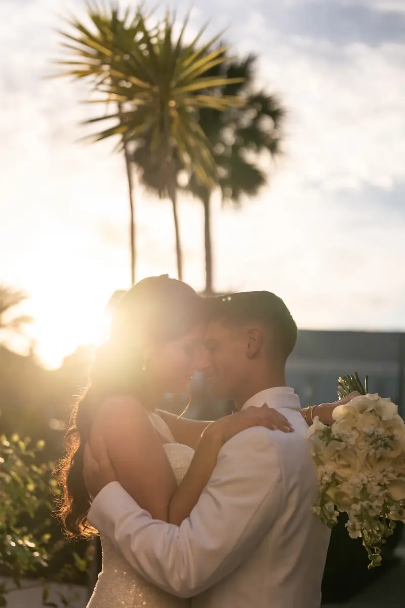 Couple silhouette kiss at sunset with palm trees and sun flare