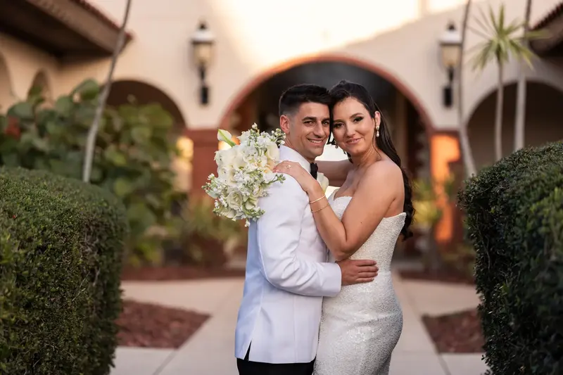 Couple embrace in Spanish-style courtyard with arches and hedges