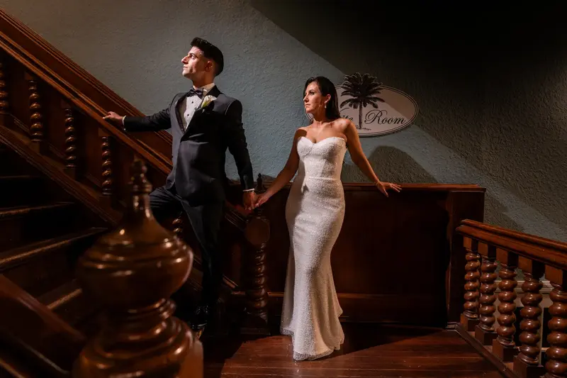 Dramatic portrait of couple descending grand staircase holding hands