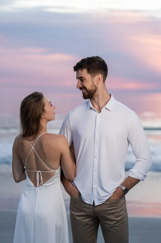 Colleen glances back at Thomas, her white dress's strappy back visible against the softening sunset light.