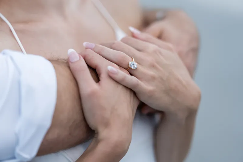 Close-up of two hands with a diamond engagement ring visible on one finger at Vilano Beach.