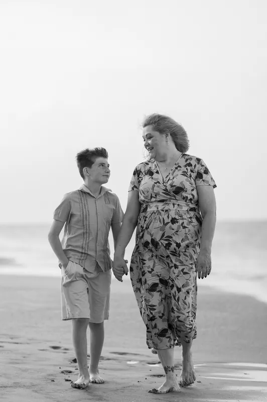 Black and white portrait of a young boy and woman walking barefoot along the wet sand at St. Augustine Beach.