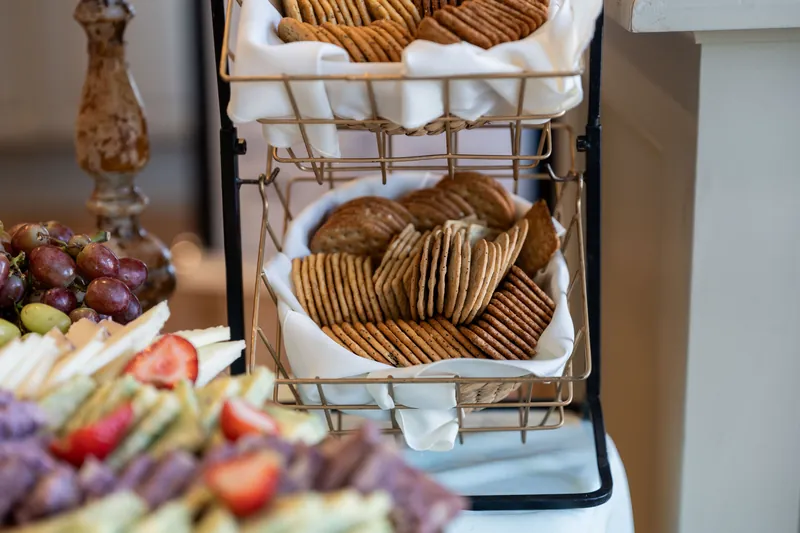 Tiered wire basket displays golden croissants wrapped in white tissue with fresh berries nearby.