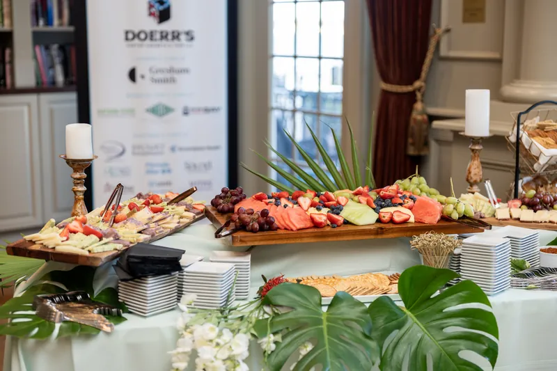 Charcuterie and cured meats arranged on wooden boards at River House Events, with a Doerrs sponsor banner nearby.