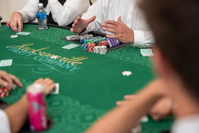 Hands deal cards and manage poker chips across a green gaming table during the casino activity.