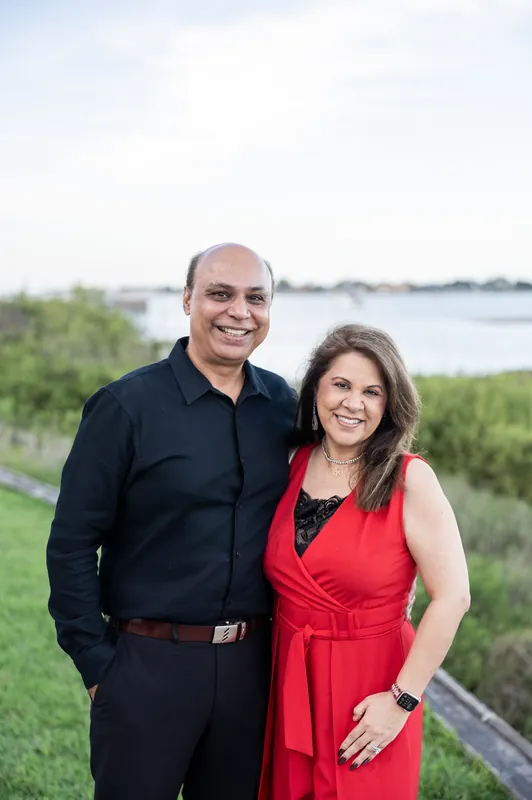 Two people stand arm in arm on the waterfront lawn overlooking the marsh and river at River House Events, St. Augustine.