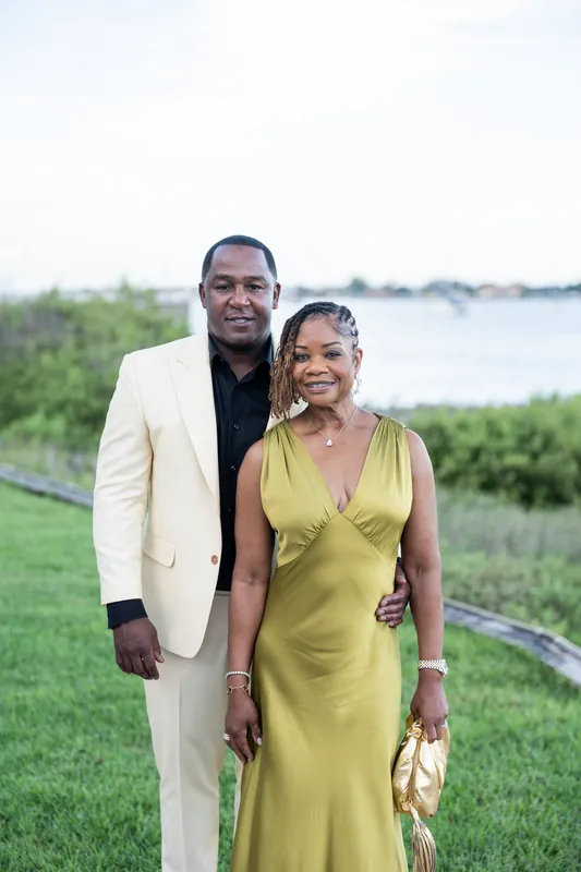 A couple poses together on the grassy grounds with the St. Augustine waterway and marsh visible behind them.