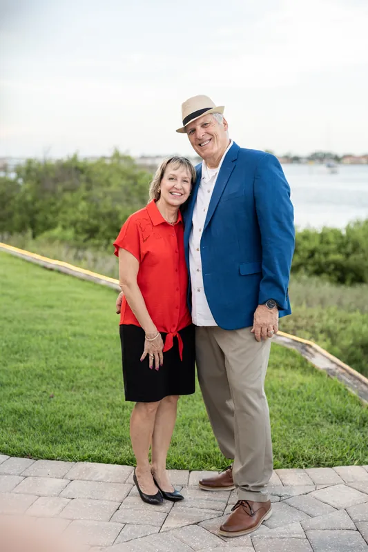 Two guests pose on the lawn with the river landscape behind them at the venue.