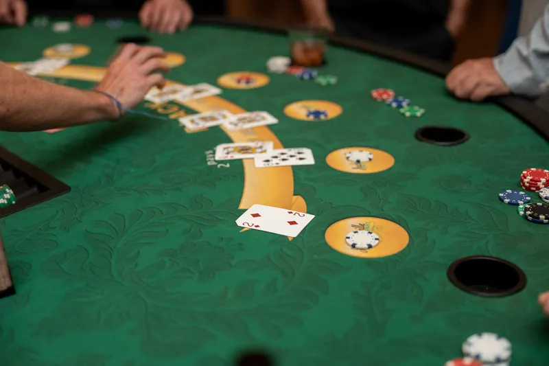 Blackjack cards and betting chips scatter across the green felt as multiple players' hands frame an active round of play.