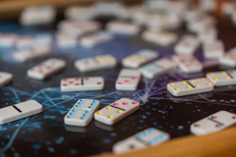Closeup of a wooden roulette wheel with numbered sections and casino chips scattered across its dark surface during gameplay.