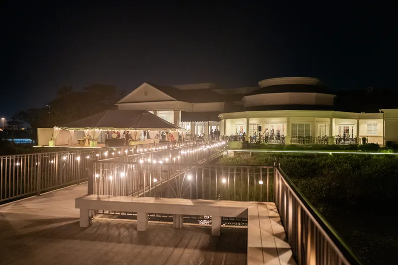 Candlelit wooden deck and illuminated buildings at River House Events create an evening glow.