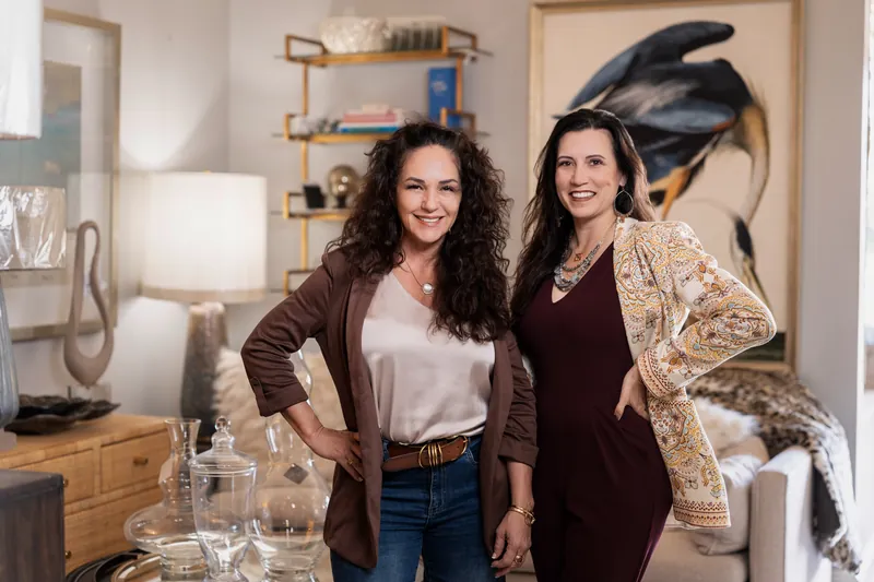 Valerie and Natalie standing side by side in the ADG Interiors showroom with glass vases and styled shelving