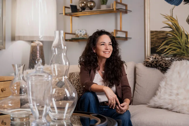 Valerie looking off-camera and smiling with glass vases in the foreground and showroom decor behind her