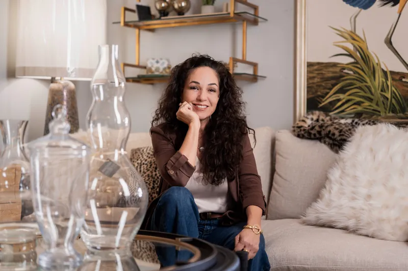 Valerie resting her chin on her fist with a warm smile, surrounded by styled decor and a heron painting