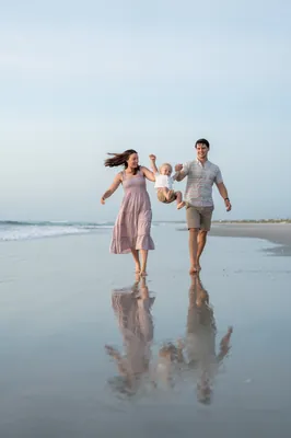 Jourdan and her partner run hand-in-hand through the shallow surf at St. Augustine Beach, their reflections visible