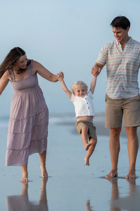 Jourdan and her family swing their young son between them while wading through shallow water at St. Augustine Beach.
