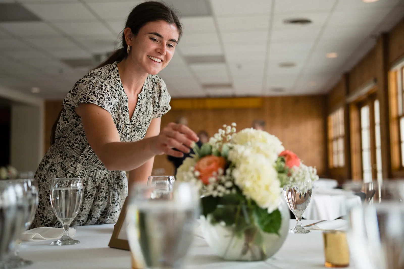 A Coastal Celebrations coordinator arranging a floral centerpiece during wedding reception setup.