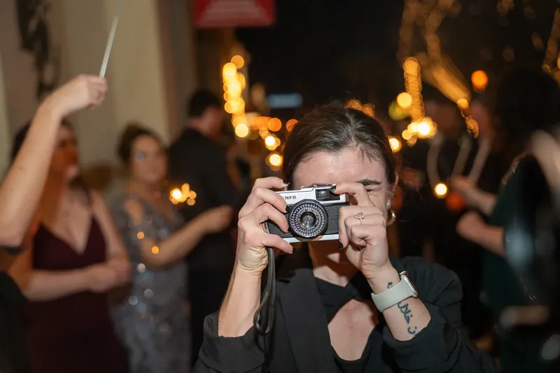 A Coastal Celebrations coordinator photographing a wedding sparkler send-off on a vintage film camera.