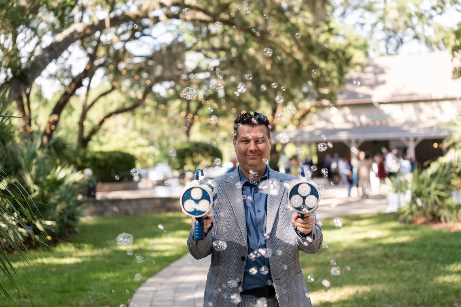 Kris of Footloose Entertainment holding two bubble machines during a wedding, bubbles filling the air.
