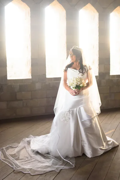 Bride with flowing veil backlit by gothic windows inside Castle Ottis St. Augustine