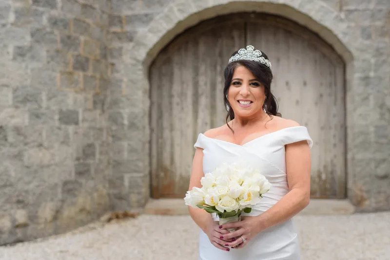 Bridal portrait in front of arched wooden doors with white rose bouquet at Castle Ottis St. Augustine