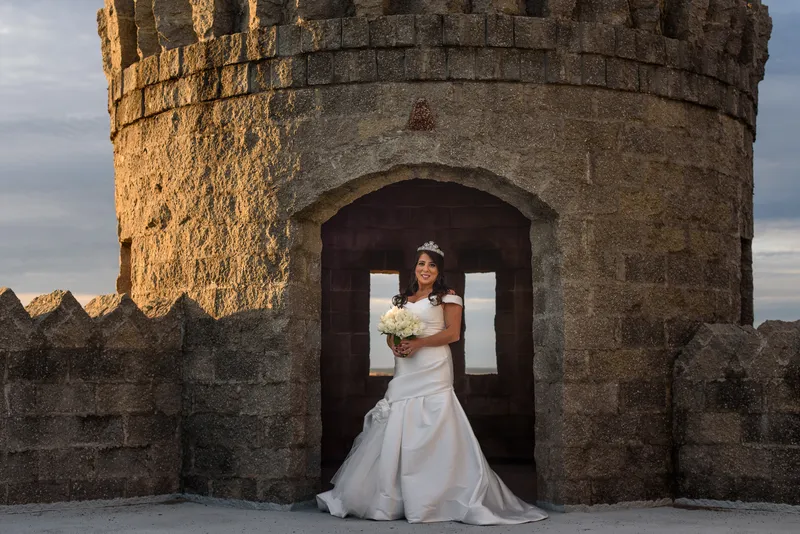 Bride on Castle Ottis rooftop at golden hour with tower turret and ocean views St. Augustine