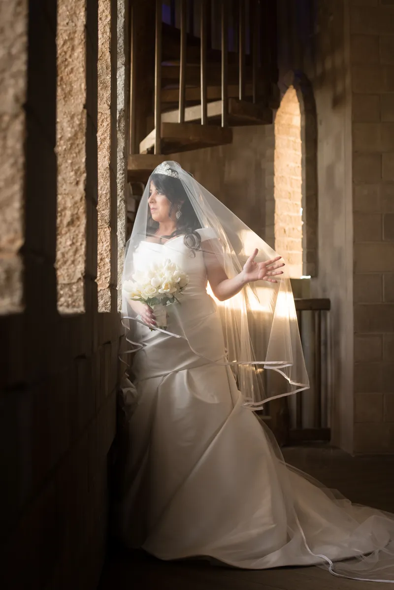 Bride in golden window light reaching toward coquina wall at Castle Ottis St. Augustine