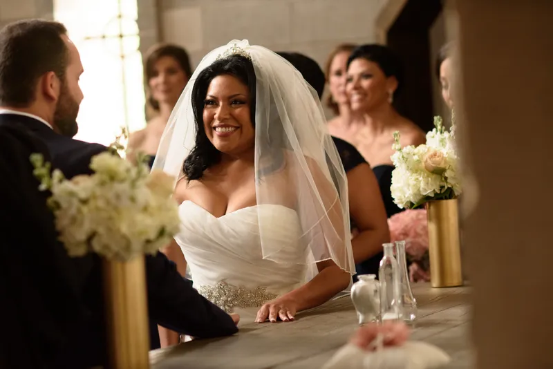 Bride smiling at groom during ceremony with bridesmaids watching at Castle Ottis wedding