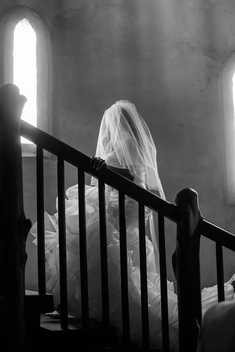 Black and white artistic portrait of bride on spiral staircase with gothic windows at Castle Ottis
