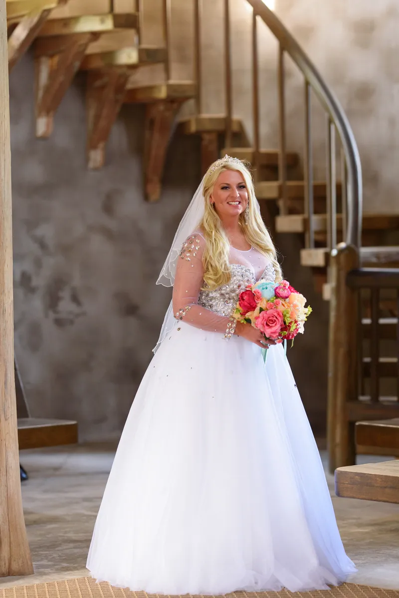 Bridal portrait with colorful rose bouquet and wooden spiral staircase in background at Castle Ottis St. Augustine