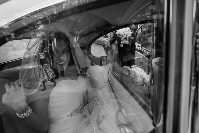 Black and white artistic shot of bride in vintage car with wedding party reflections at Castle Ottis