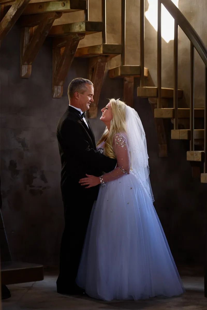 Romantic couple portrait embracing by spiral staircase with golden backlight at Castle Ottis wedding venue