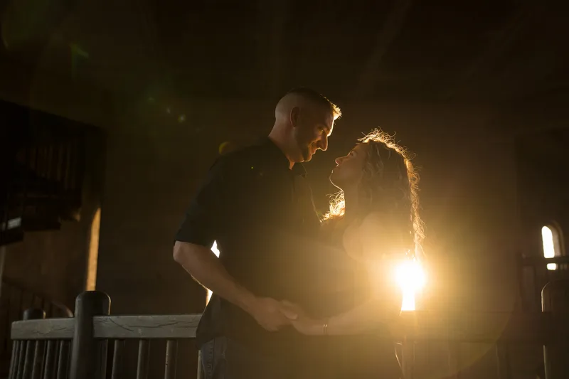 Dramatic backlit silhouette of engaged couple at Castle Ottis with golden sunburst