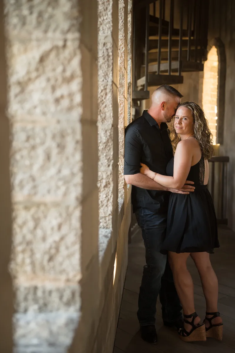 Couple embracing against coquina wall during golden hour engagement session at Castle Ottis