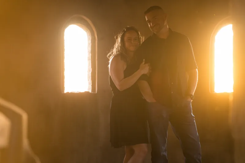 Couple portrait with dual gothic windows backlit by golden sunset at Castle Ottis St. Augustine