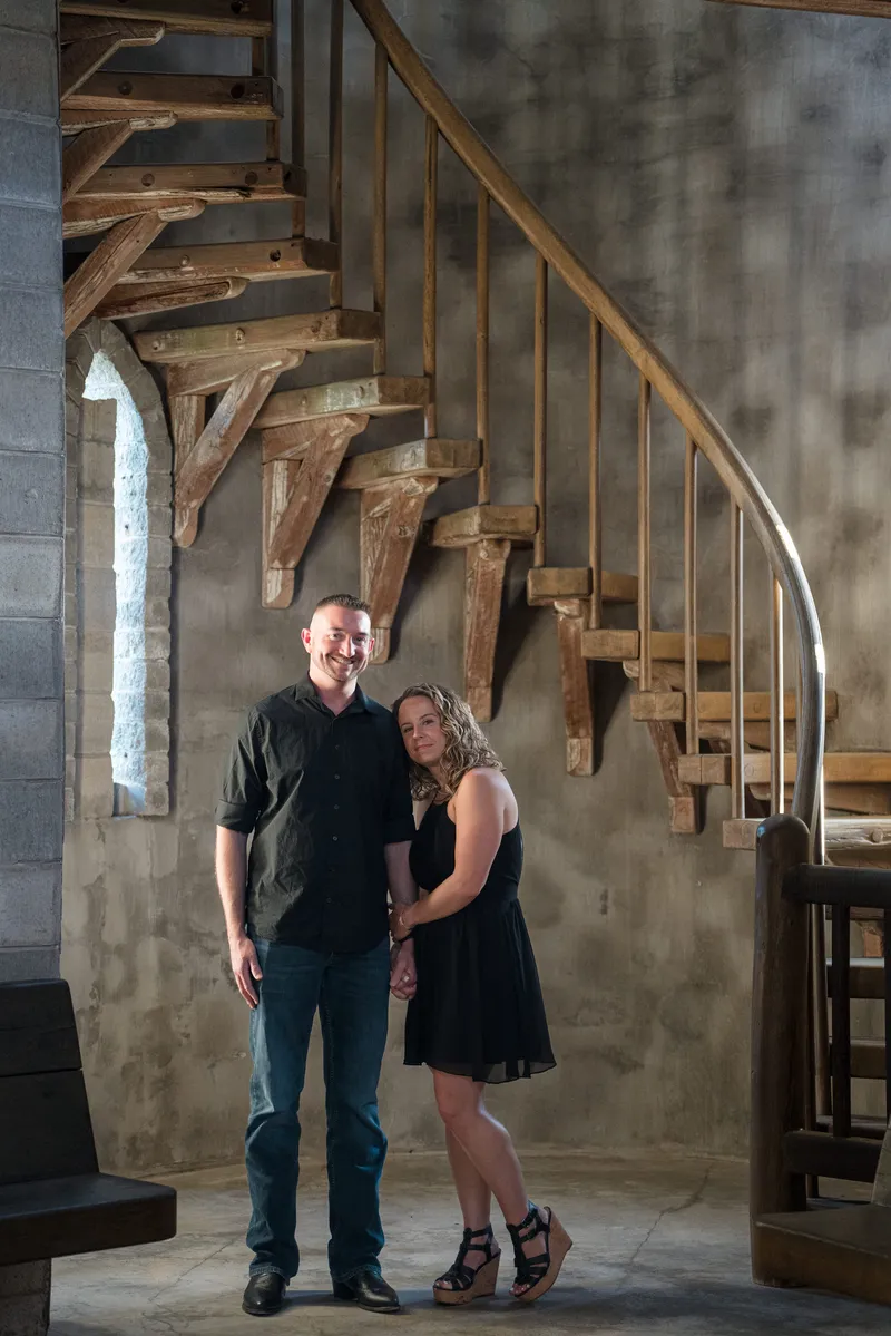 Engagement portrait under wooden spiral staircase with gothic window light at Castle Ottis