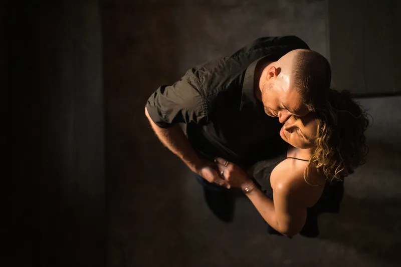 Overhead intimate portrait of couple embracing with dramatic light on coquina floor at Castle Ottis