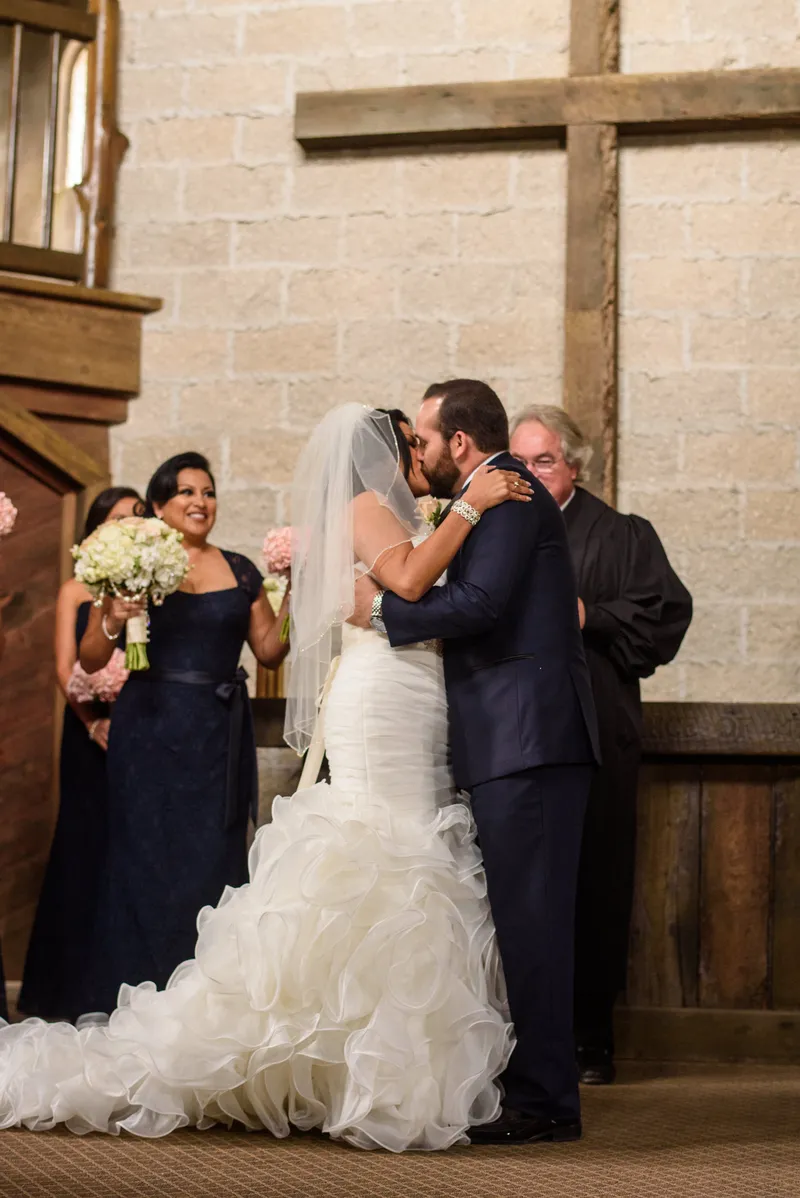 First kiss at the altar with coquina stone walls and wooden cross at Castle Ottis wedding