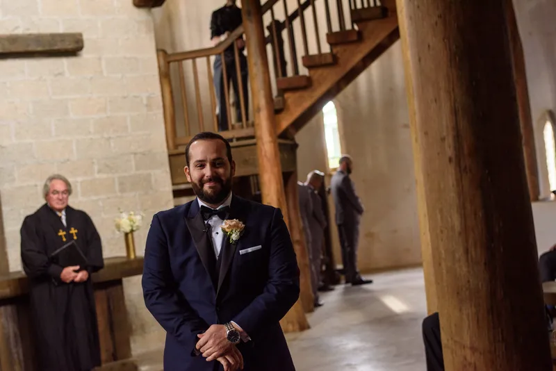 Groom waiting at altar with officiant and wooden spiral staircase at Castle Ottis wedding venue in St. Augustine