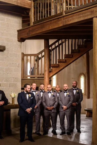 Groom and groomsmen portrait under wooden spiral staircase with coquina walls at Castle Ottis