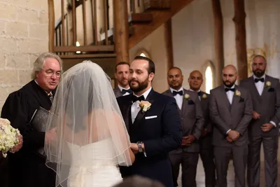Bride and groom exchanging vows at altar with officiant during Castle Ottis wedding ceremony