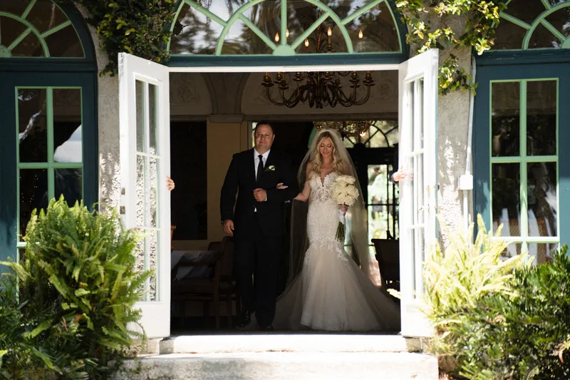 Father walking bride through French doors from the mansion at Club Continental with chandelier visible