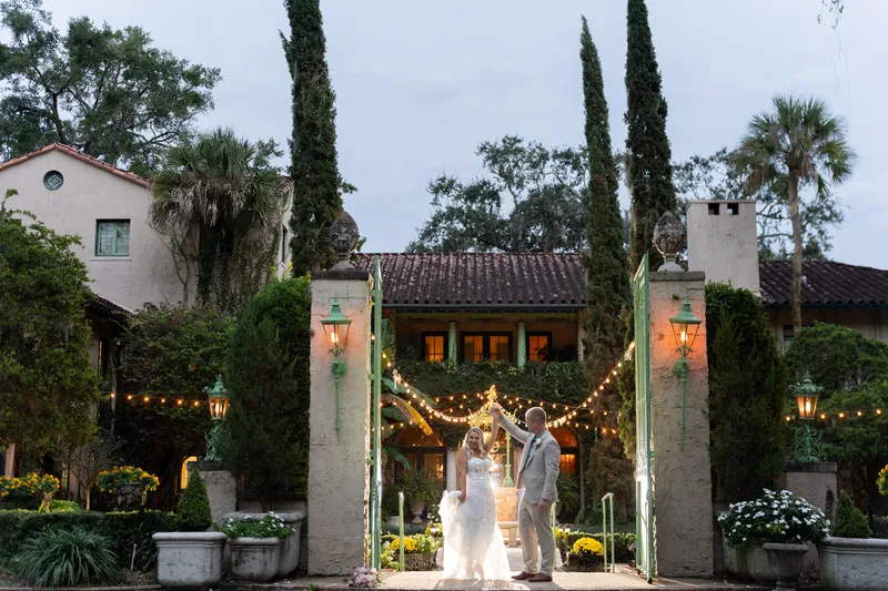 Couple sharing their first dance under string lights at the entrance gates of Club Continental