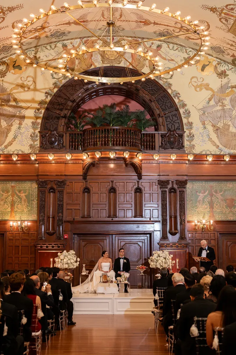Wedding ceremony in Flagler College Dining Hall with painted murals and chandelier