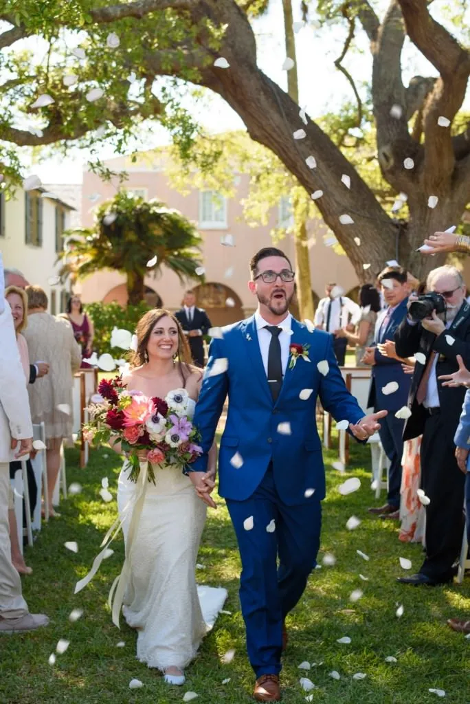 Couple showered with flower petals leaving wedding