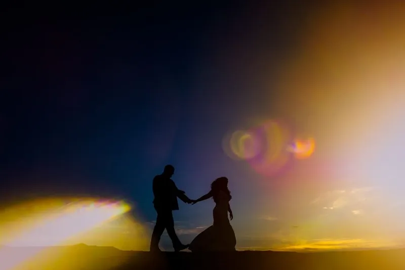 Wedding day sun flare as couple walks hand in hand