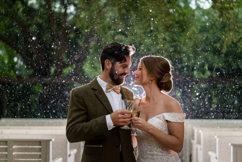 Bride and groom cheersing in the rain